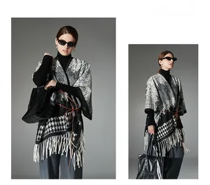 Detail of black and white houndstooth wool poncho featuring elegant white fringe and leather belt