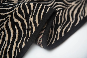 Dettaglio macro del tessuto a maglia zebrata con bordo nero e trama intrecciata