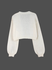 Detailed close-up of white knit cardigan texture with ribbed cuffs and hem finishing