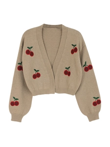 Close-up of beige knit cardigan featuring intricate red cherry embroidery and V-neck detail