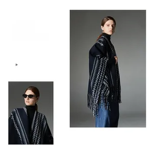 Detail view of navy blue knitted poncho with white geometric Greek key patterns and tassels