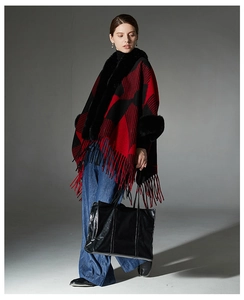 Detail of red and black plaid knit shawl featuring plush faux fur collar and fringe tassels