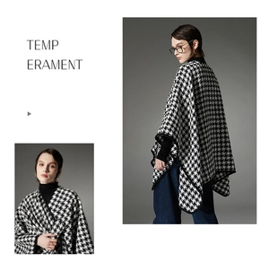 Close-up detail of the black and white houndstooth pattern and buckle of the stylish poncho