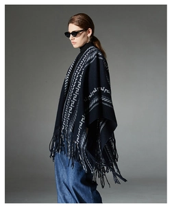 Detail of dark blue knit shawl featuring contrast geometric patterns and long fringe trim