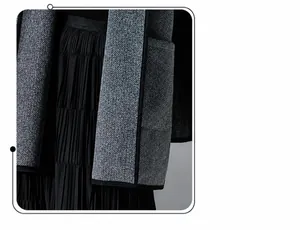 Detail shot of grey herringbone wool cape with black piping and pleated skirt texture