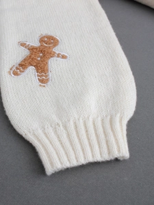 Close-up of white knit sleeve with ribbed cuff and cute gingerbread man patch