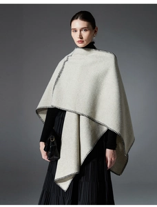 Detail of light gray wool shawl featuring distinctive black whipstitch edges and minimalist cut