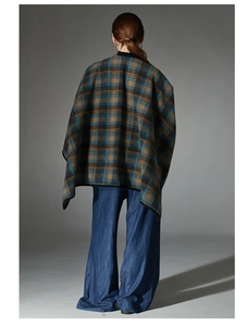 Rear view of a loose plaid poncho cape with brown and blue patterns and black piped edges