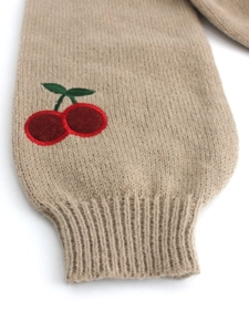 Detailed view of knitted sleeve cuff featuring 3D cherry embroidery and ribbed texture