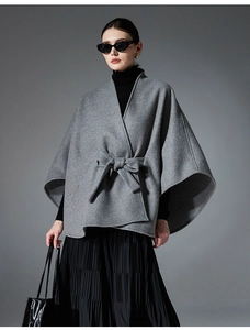 Detail showing elegant grey wool blend cape with waist bow tie and smooth fabric texture