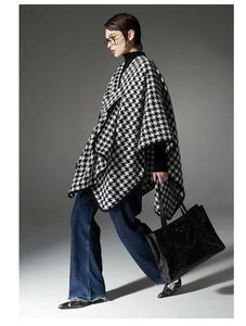 Detail of black and white houndstooth poncho featuring clean black piped edges and loose fit