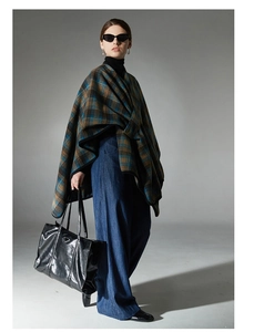 Detailed texture of a plaid shawl cloak featuring woven wool fabric and edge stitching