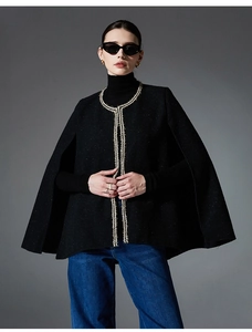 Detail of tweed cape jacket showing black fabric and gold woven trim with open front style