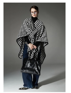 Detailed view of women's black and white houndstooth poncho shawl with buckle for autumn fashion