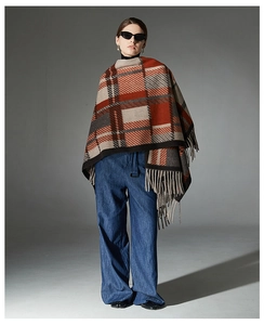 Detail of camel plaid wool shawl with fringe trim on a model in a fashion studio setting