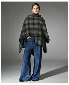 Detail view of winter plaid poncho with fringe edges and classic tartan pattern style
