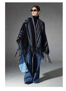 Detail of navy blue poncho shawl with white geometric jacquard and long tassel fringe