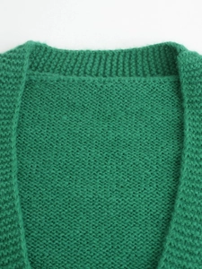 Close-up detail of grass green knit sweater showing ribbed neckline and wool blend texture