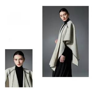 Detail of light beige knitted shawl with black whipstitch edges and premium soft texture