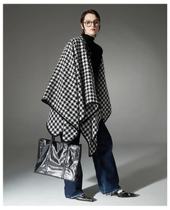 Detail of classic black and white houndstooth poncho shawl with stylish buckle closure