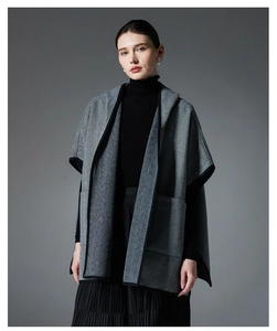 Detail of grey herringbone hooded cloak with black contrast trim and fine wool texture