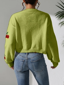 Detail view of avocado green knit sweater with red cherry embroidery on sleeves
