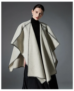 Detail of cream double-sided shawl featuring black contrast stitching and elegant wool texture