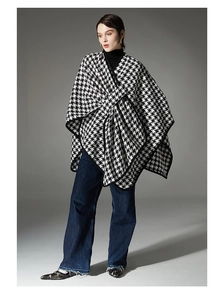 Close-up of houndstooth poncho with black trim detailing and thick fabric texture