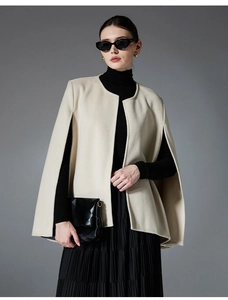 Detail of off-white wool poncho featuring open front and arm slits for elegant styling