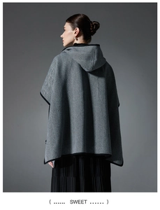 Detail of grey herringbone hooded poncho with black piping and thick wool texture