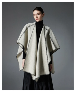 Detail of light beige cape coat with black blanket stitch edges and textured wool fabric