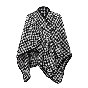 Detail view of the black and white houndstooth knit cape with buckle and black piping