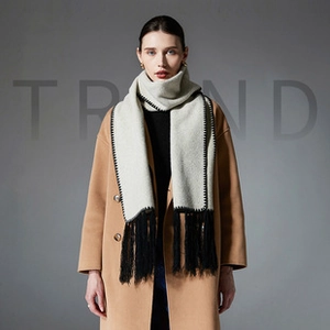 Detailed view of light gray scarf with black stitching and long fringes on a cashmere coat