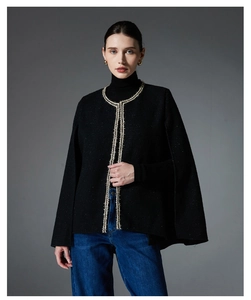 Close-up of black tweed cape jacket featuring elegant gold metallic braided trim details