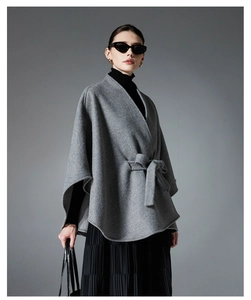 Detail of the high-quality grey wool blend texture and waist belt on a fashion cape coat
