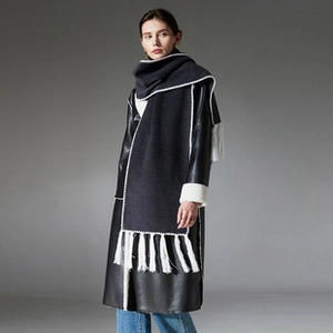 Close-up of premium dark grey wool scarf with white contrast stitching and thick fringe