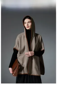 Detail of herringbone hooded cloak featuring dark brown trim and premium woven texture