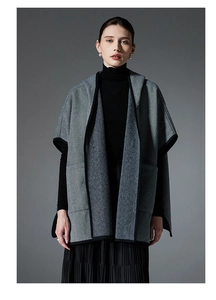 Detailed view of grey herringbone wool cape featuring premium black contrast edge binding