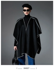 Detail of black knit shawl with white contrast stitching and elegant draped hemline