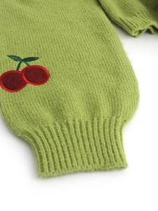 Detail of green knitted cuff with ribbing and delicate red cherry embroidery