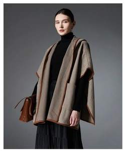Detail of herringbone wool poncho with hooded design and contrast binding finish