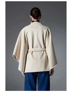 Rear view of beige wool blend poncho coat with waist belt and wide sleeves detail