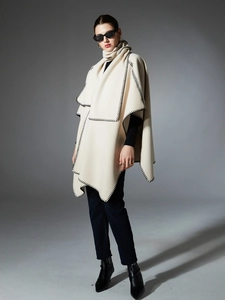 Detail of beige wool shawl cloak with black blanket stitch edges and elegant drape