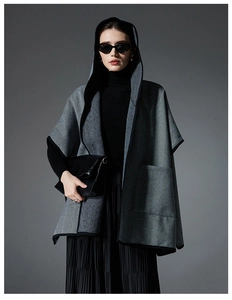 Detailed view of grey herringbone hooded cape with large pockets and black trim