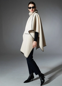 Detail of cream knit shawl featuring black whipstitch edging and a warm turtleneck collar