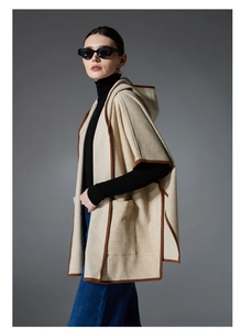 Detail of plaid hooded poncho with brown piping and large pockets on premium fabric