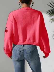 Detailed back view of pink knit cardigan featuring red cherry embroidery on sleeves