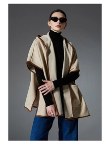 Detail of checkered hooded poncho with leather-trimmed edges and functional pockets