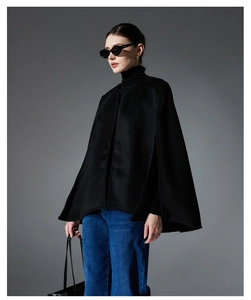Detail view of a black sleeveless wool cape jacket styled with denim for a chic autumn look