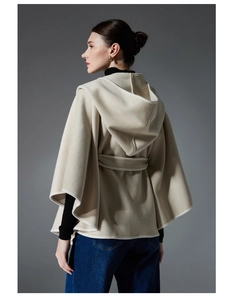 Detail view of beige hooded cape with soft wool texture and elegant waist belt tie